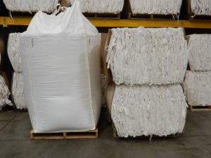 large white bulk bag on wooden pallet next to box full of stacked, empty bulk bags
